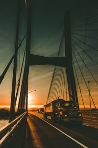 Sunset view of a cable-stayed bridge with a semi-truck driving and clear skies