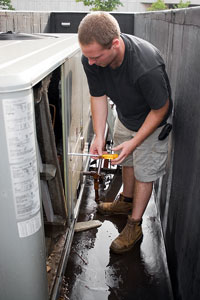 HVAC technician measuring refrigerant levels in an outdoor air conditioning unit