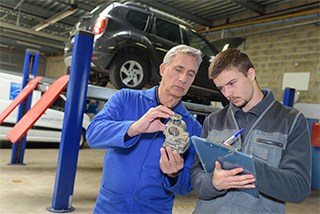 Two mechanics inspecting an automotive part.