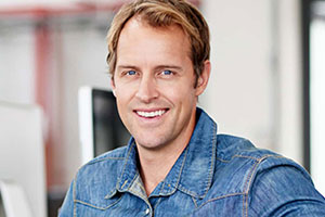 A smiling man in a denim shirt.