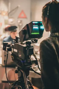 Female camera operator filming a scene with a professional video camera in a studio setting