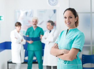 medical assistant stands in front of other medical professionals in clinical setting