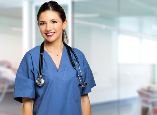 Female Nurse in blue scrubs with stethoscope standing in a modern hospital corridor.